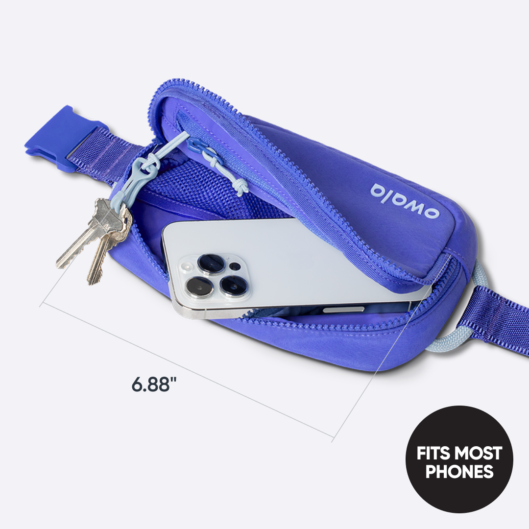 Owala Daily Crossbody in Al Fresco, peach belt bag shown open with a smartphone and keys inside, dimensioned at 6.88 inches wide, with badge reading "FITS MOST PHONES"